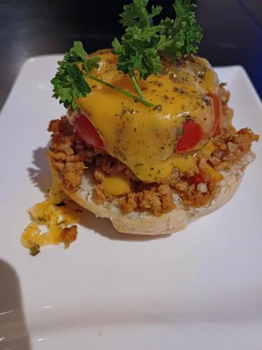 a sandwich with meat and cheese on a white plate at Jayla Homestay in Maun