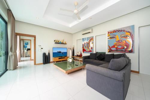 een woonkamer met een bank en een tafel bij Relax & Enjoy Stay! Elegant 3BR Pool Villa Talosy in Rawai Beach