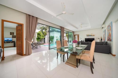 a dining room and living room with a glass table and chairs at Relax & Enjoy Stay! Elegant 3BR Pool Villa Talosy in Rawai Beach