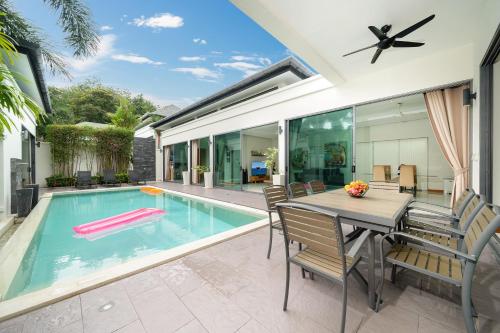 een eetkamer met een tafel en een zwembad bij Relax & Enjoy Stay! Elegant 3BR Pool Villa Talosy in Rawai Beach