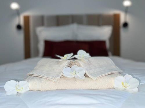 a bed with two towels and white flowers on it at T1, Le Bec Rose, neuf, 8 min aéroport in Sainte-Clotilde