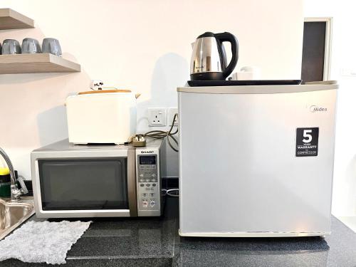 a microwave and a coffee pot on top of a refrigerator at HillLand Suites in Ayer Keroh