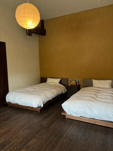 two beds in a room with a chandelier at 土肥邸母屋 in Tateyama