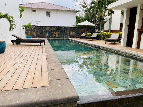 a swimming pool with a wooden deck and a house at Belle Haven GF 1bedroom flat in Mont Choisy