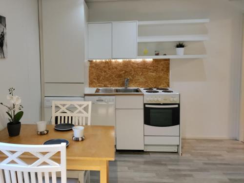 una cucina con elettrodomestici bianchi e tavolo in legno di Puisto mökki a Rauma