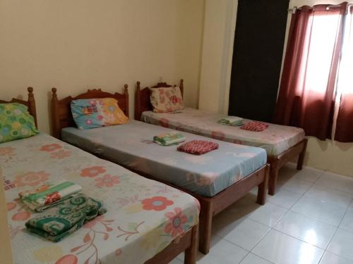 a room with three twin beds and a window at Bee Hub Pension in Surigao