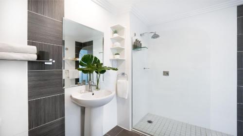 a white bathroom with a sink and a shower at Apartment 212 Sebel Kiama in Kiama