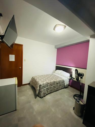 a bedroom with a bed and a purple wall at Gran Hotel Victoria in Tacna