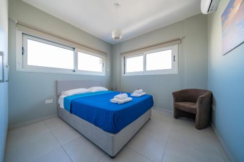 a bedroom with a blue bed and a chair at Majestic Sunset Salt Lake Views 300m From Beach in Larnaka