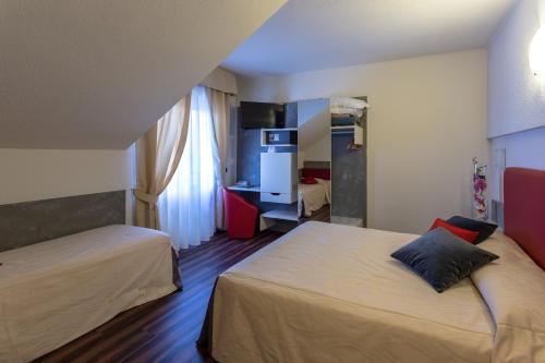 a hotel room with two beds and a refrigerator at Hotel Le Palme in Dormelletto
