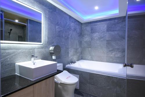 a bathroom with a sink and a tub and a toilet at ZJ Motel in Hsinchu City