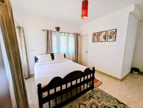 a bedroom with a bed with white sheets and a window at Bohemian Hideaway by Futurve in Kodaikānāl