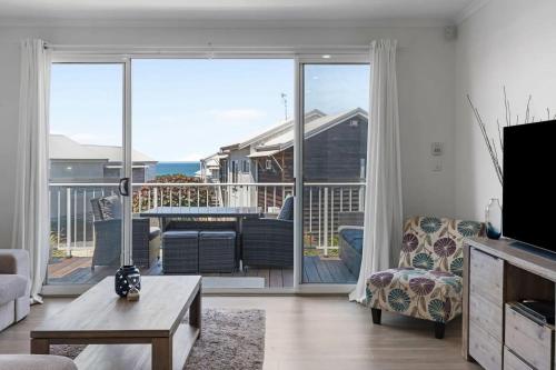 a living room with a view of a balcony at Villa with Seaside Soul Newly Renovated in Caves Beach