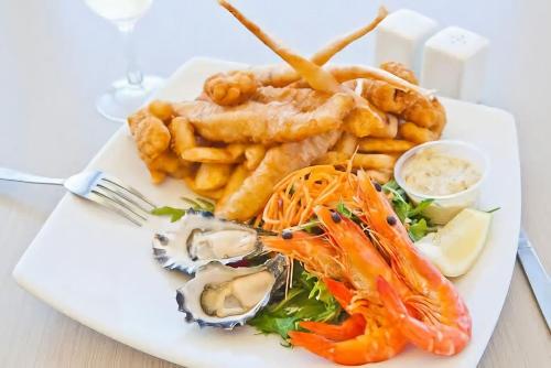 a plate of food with seafood and french fries at Villa with Seaside Soul Newly Renovated in Caves Beach