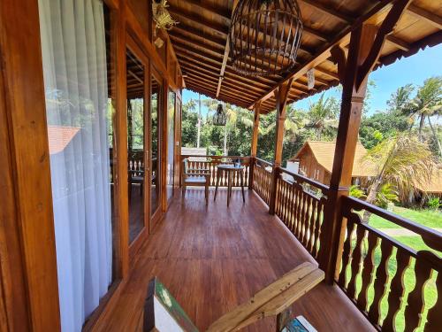 a porch of a wooden house with a table and chairs at Bhalance Retreat in Padangbai