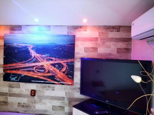 uma grande televisão de tela plana na parede com uma pintura em Guest House Sofia em Sandanski