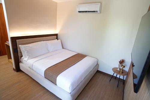 a small bedroom with a white bed and a air conditioner at Gonzales Hotel in Cauayan