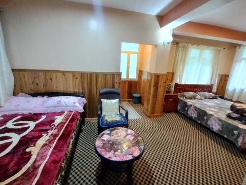 a bedroom with two beds and a table in it at Lepcha Homestay Darjeeling in Darjeeling