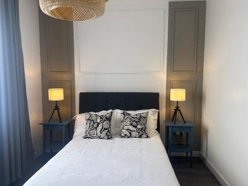 a bedroom with a bed with pillows and two lamps at Behomu Apartments Kampala in Kira