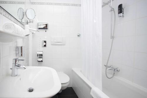 a bathroom with a sink and a toilet and a shower at Centro Hotel Mondial München City, Trademark Collection by Wyndham in Munich