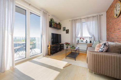a living room with a couch and a large window at Exceptional Apartment in Warsaw with Parking by Noclegi Renters in Warsaw