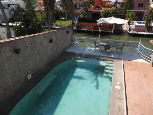 a large swimming pool with a table and an umbrella at Casa en el canal barra de navidad con 5 recamaras in Barra de Navidad