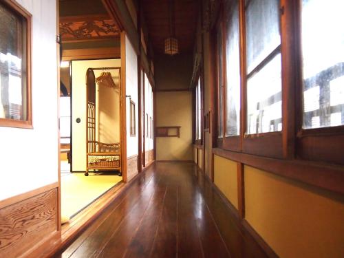 an empty room with wooden floors and windows at ゲストハウス柚 in Shingu