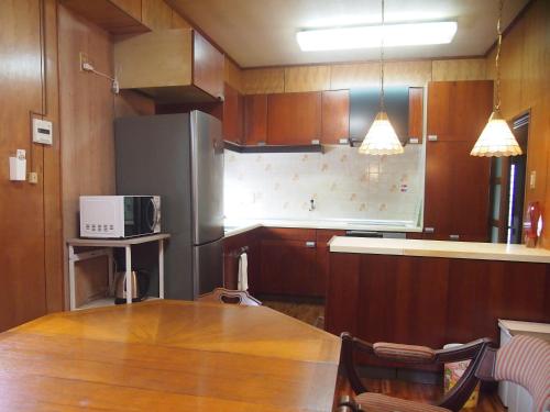 a kitchen with a table and a stainless steel refrigerator at ゲストハウス柚 in Shingu