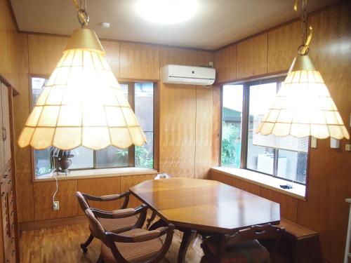 a dining room with a wooden table and two lights at ゲストハウス柚 in Shingu