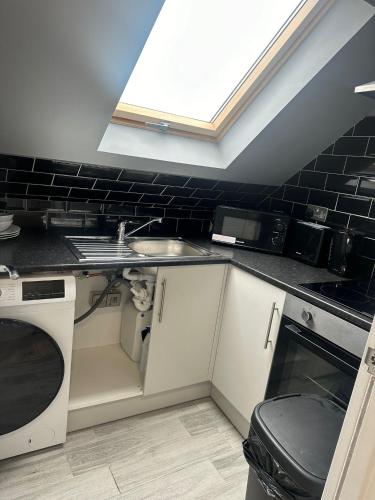 a small kitchen with a sink and a window at Letzi Ensuite, 15 Min to Heathrow, Fast WiFi in Hayes
