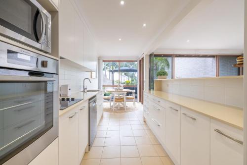 a kitchen with white cabinets and a large window at The Moorings 23 4 Cromarty Rd air con pool and waterfront in Soldiers Point