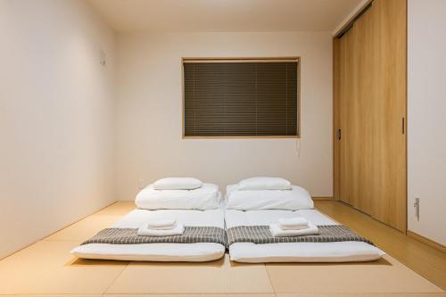 three beds in a room with a window at Irodori Hotel KOU in Fukuoka