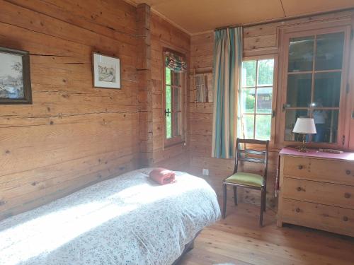 a bedroom with wooden walls and a bed and a chair at Chalet de La Tour Mayens de Sion 4 Vallées in Agettes