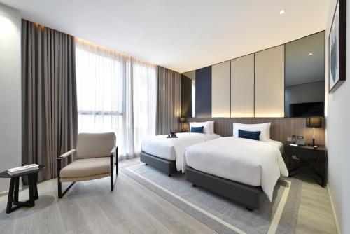 a hotel room with two beds and a chair at GM Estate Hotel and Executive Apartments Sukhumvit 20 in Bangkok