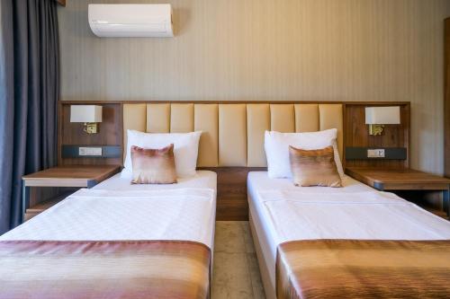 a hotel room with two beds and two tables at Days Inn by Wyndham Alanya in Alanya