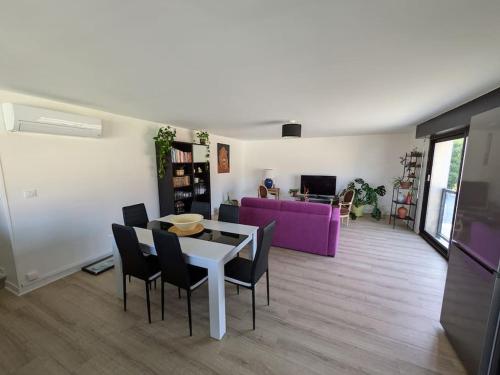 - un salon avec une table, des chaises et un canapé violet dans l'établissement Location appartement, à Cézac