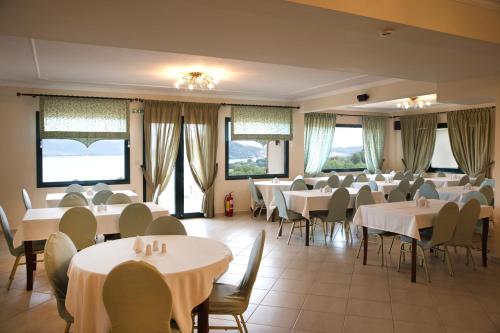 a dining room with white tables and chairs and windows at Hotel Agnanti Unique Hospitality in Kastoria