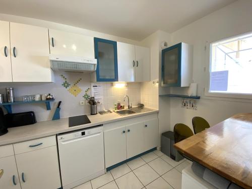 - une cuisine avec des placards blancs, un évier et une table dans l'établissement VILLA MARINA 2 pieces avec parking et wifi centre, à La Teste-de-Buch