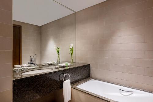 a bathroom with a sink and a mirror at Grand Millennium Al Wahda Hotel and Executive Apartments Abu Dhabi in Abu Dhabi