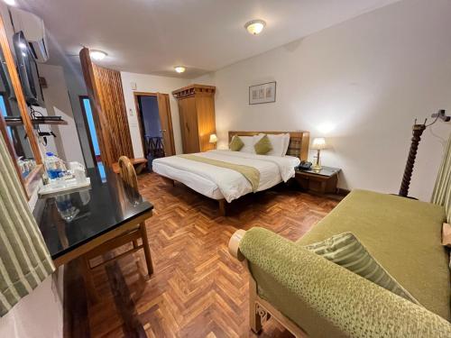 a hotel room with a bed and a couch at Manuallaya The Resort & Spa in Manāli