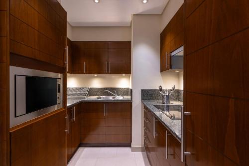 a kitchen with wooden cabinets and sinks and a tv at Grand Millennium Al Wahda Hotel and Executive Apartments Abu Dhabi in Abu Dhabi
