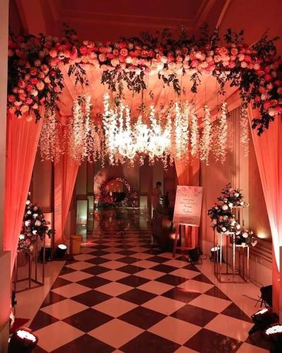 a lobby with a checkered floor and chandeliers and flowers at Hotel Paras in Dera Bassi
