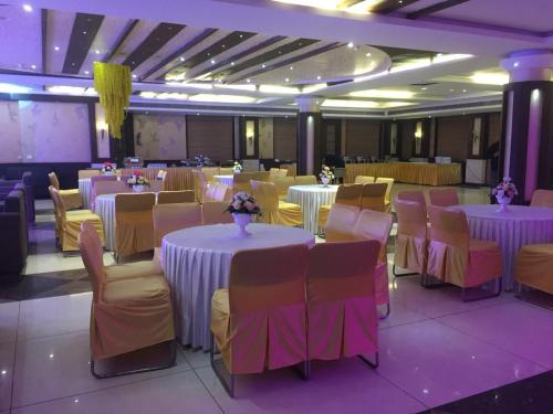 a banquet hall with white tables and chairs with flowers on them at Hotel Paras in Dera Bassi