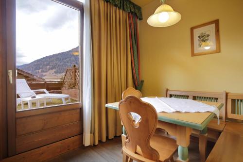 a dining room with a table and a balcony at Park Hotel Leonardo in Moena