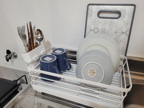 a white rack in a refrigerator with plates and utensils at Liberty Shinjuku House in Tokyo