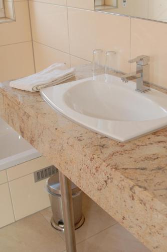 a sink in a bathroom with a marble counter top at Hotel-Restaurant Laux in Merzig