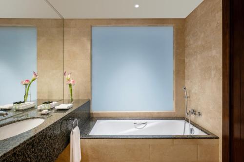 a bathroom with a tub and a sink at Grand Millennium Al Wahda Hotel and Executive Apartments Abu Dhabi in Abu Dhabi