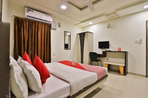 a bedroom with a bed with red pillows and a desk at Hotel O Park Inn in Rajkot