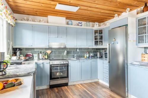 a kitchen with blue cabinets and stainless steel appliances at Big 4 bedroom house with sauna by the sea in Vaasa