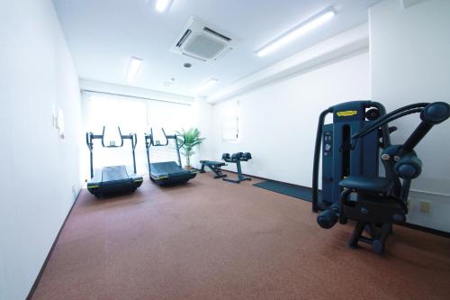 a gym with cardio equipment in a white room at Miyazaki Mango Hotel in Miyazaki